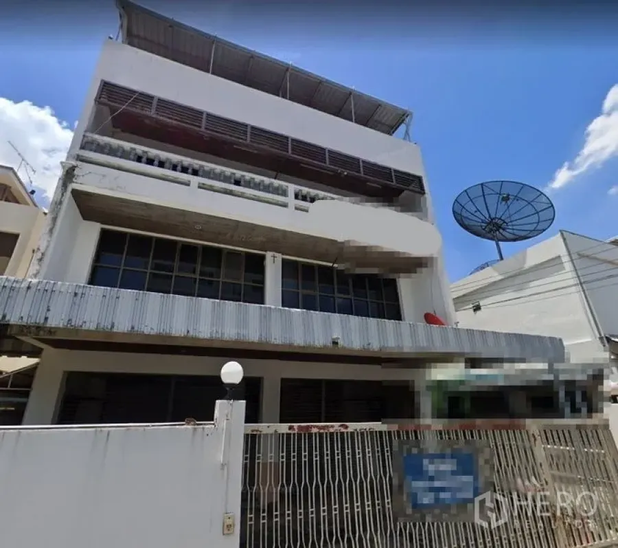 Home Office for rent in Suan Luang, Bangkok - Multi-storey home office exterior with gated fence, wide glass windows, metal awnings and rooftop cover under a bright blue sky.
