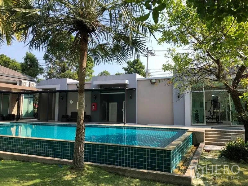 Detached House for sale in Nonthaburi - Community facility with outdoor swimming pool beside the clubhouse and trees.
