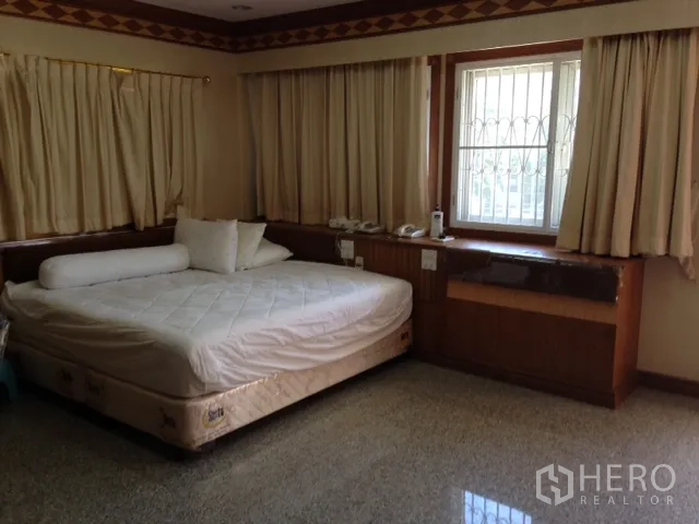 Detached House for rent in Bang Rak, Bangkok - Second bedroom featuring a large bed, built-in desk under the window and cream curtains.