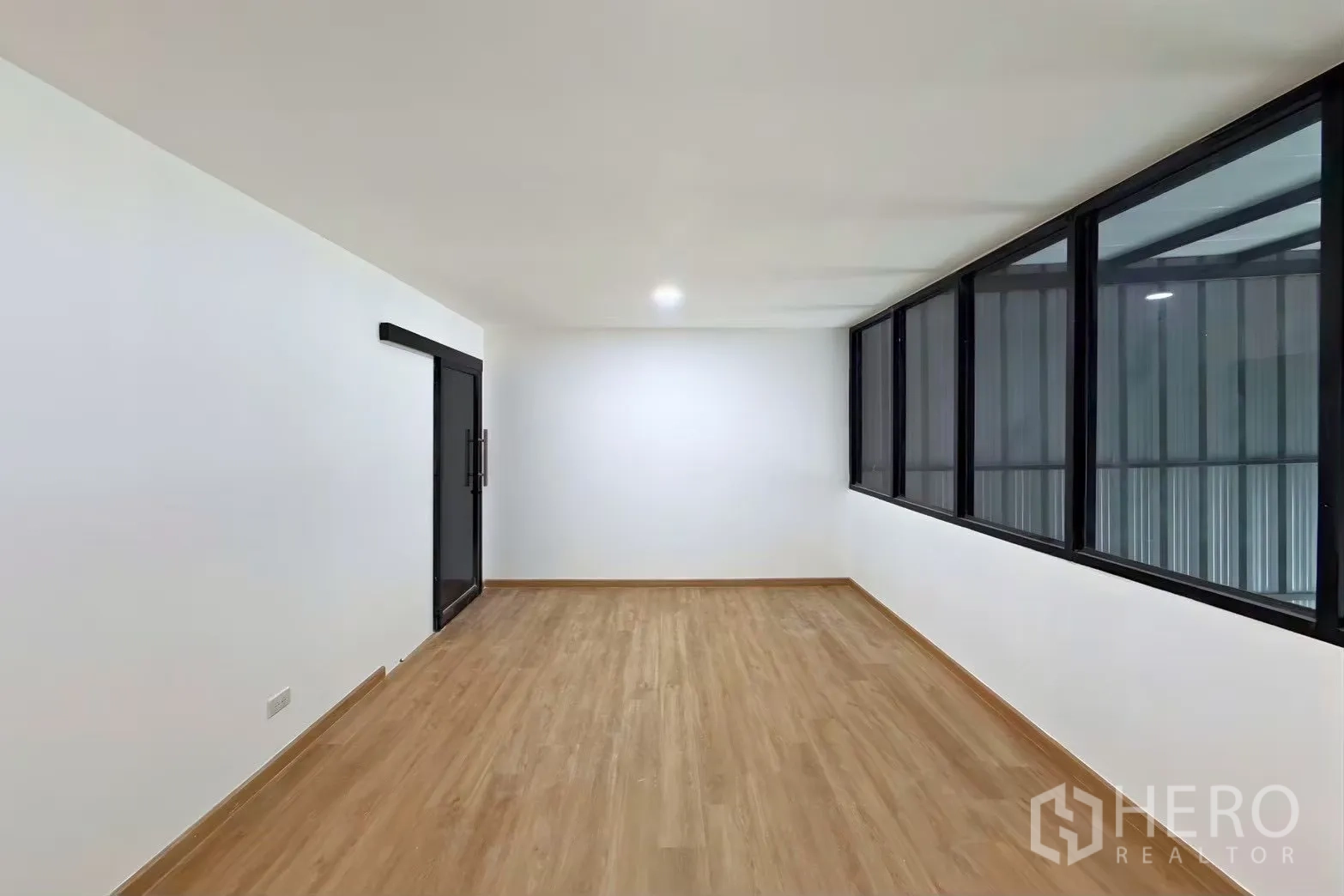 Warehouse for rent in Wang Thonglang, Bangkok - Mezzanine office room with large windows overlooking the warehouse and a sliding glass door.