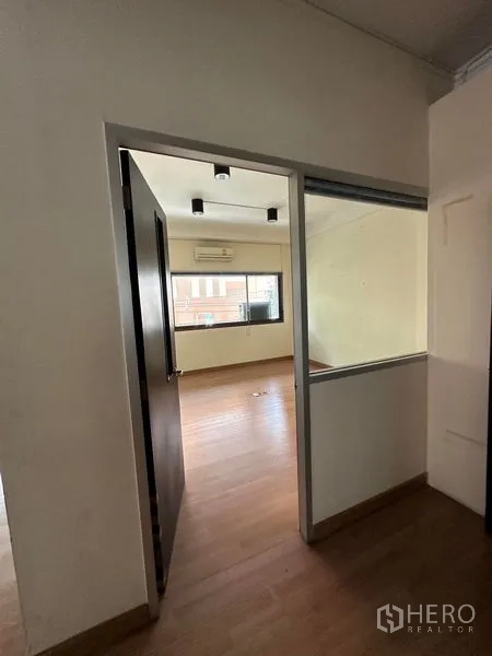 Office Space for rent in Khlong Toei, Bangkok - Entrance corridor leading to a bright office room with a window and air-conditioning unit.