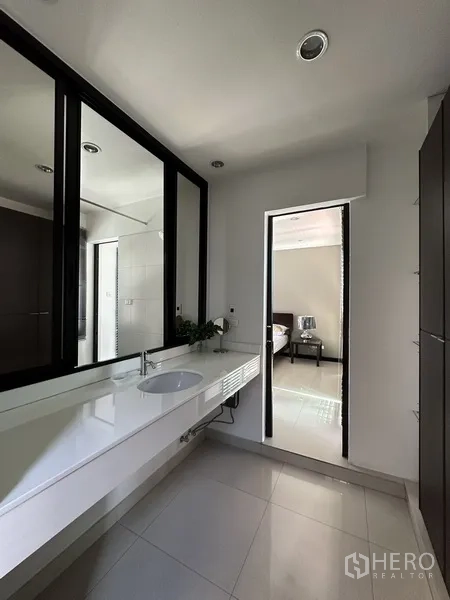 Condominium for rent in Khlong Toei, Bangkok - Ensuite vanity area with long countertop, mirror wall, and storage cabinets.