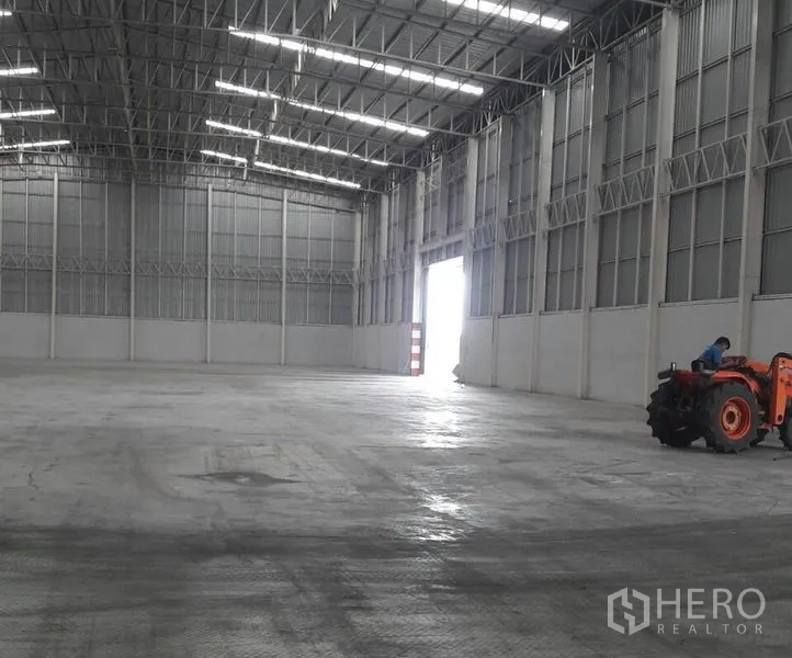 Warehouse for rent in Phra Nakhon Si Ayutthaya - Spacious warehouse floor with high ceiling and bright loading doorway for truck access.
