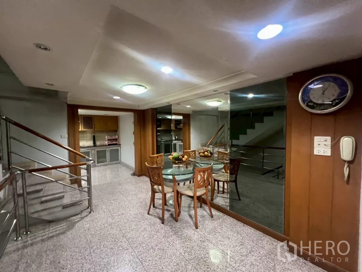 Shophouse for rent in Bang Rak, Bangkok - Upper-floor landing with stainless staircase, mirror wall and small dining area beside a pantry.