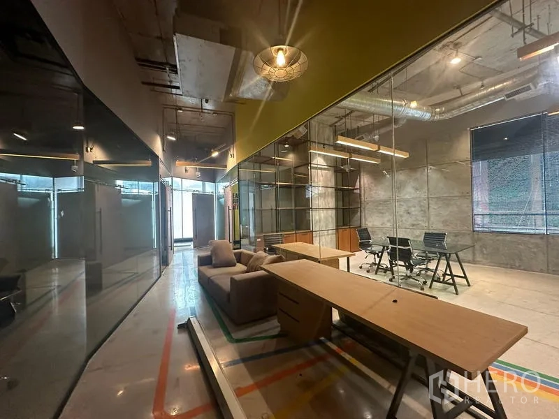 Office Space for rent - Open-plan office featuring glass partitions, sofa seating and an industrial ceiling.
