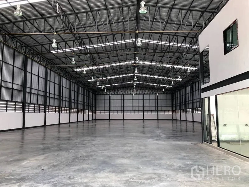 Warehouse for rent in Bang Phli, Samut Prakan - Deep interior perspective of the warehouse with smooth concrete floor and glass-partitioned office.