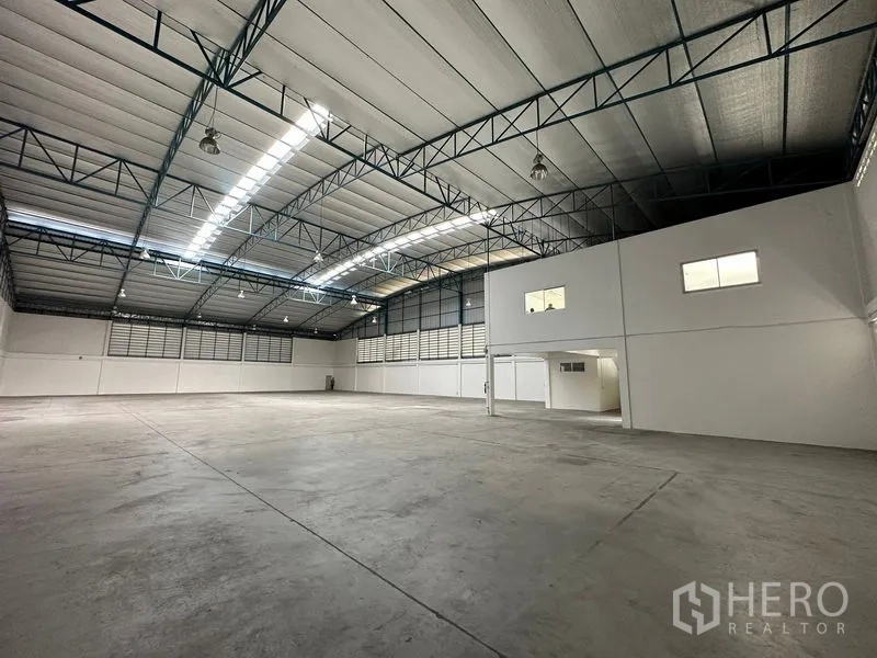 Factory for rent in Si Racha, Chon Buri - Bright warehouse interior featuring insulated roof panels, ventilation louvers and a mezzanine office section.