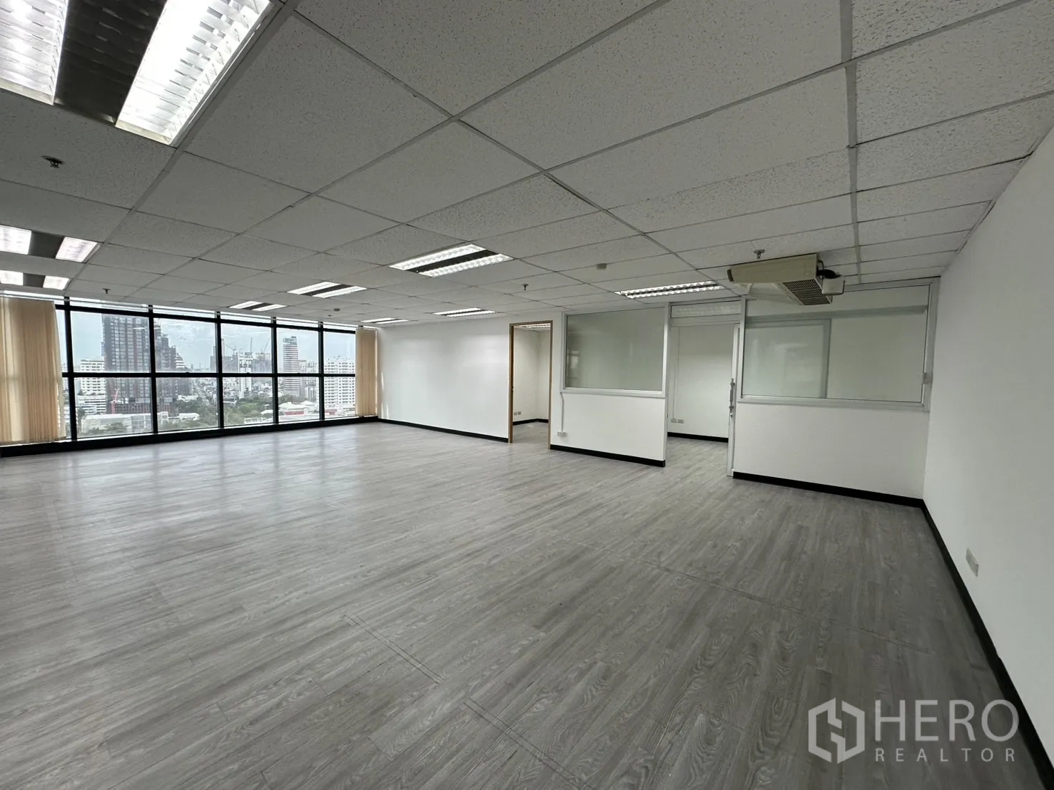 Office Space for rent in Watthana, Bangkok - Spacious office hall featuring multiple glass-partitioned rooms, blinds and wall-to-wall windows.