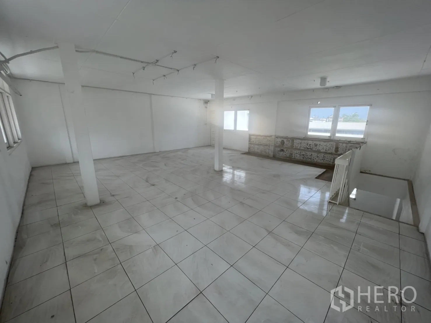 Shophouse for rent in Watthana, Bangkok - Top floor open space with white tiles, multiple windows and city sky view.