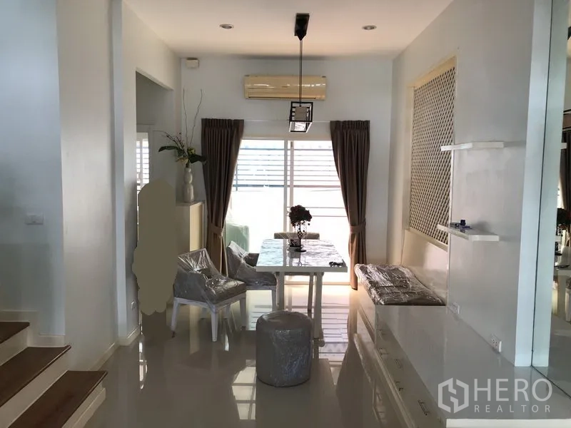 Townhouse for rent in Prawet, Bangkok - Dining area with table set, pendant light, built-in seating and sliding doors.