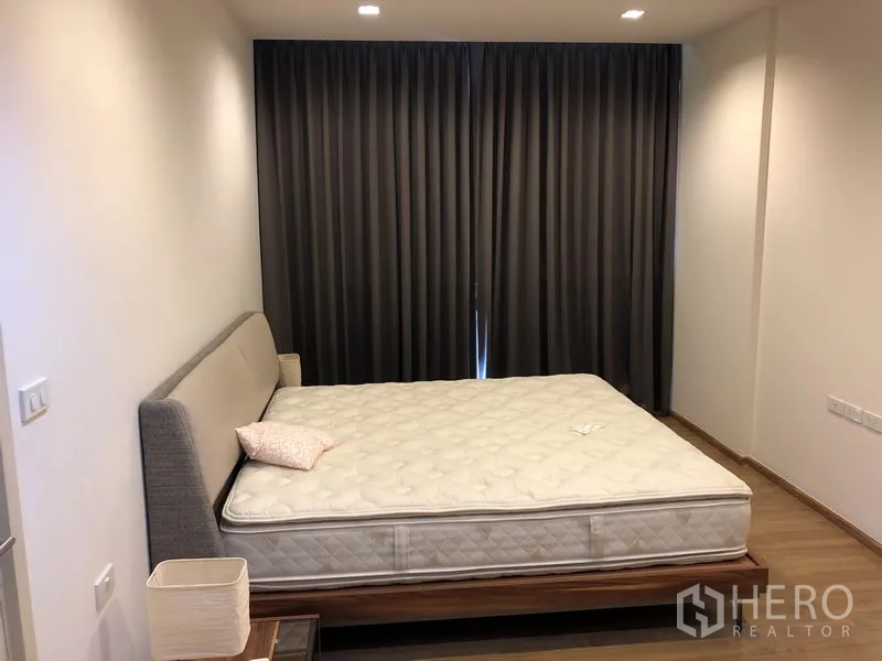 Condominium for rent in Watthana, Bangkok - Spacious master bedroom with king bed, wood floors and blackout curtains.