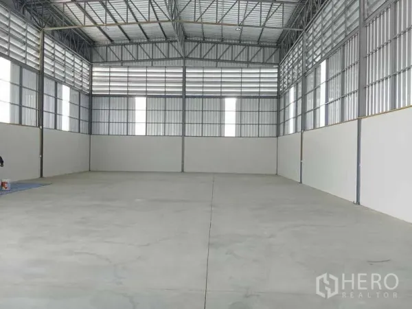 Warehouse for rent in Bang Bua Thong, Nonthaburi - Spacious warehouse interior showing high ceiling steel trusses, polished concrete floor and translucent skylight panels.