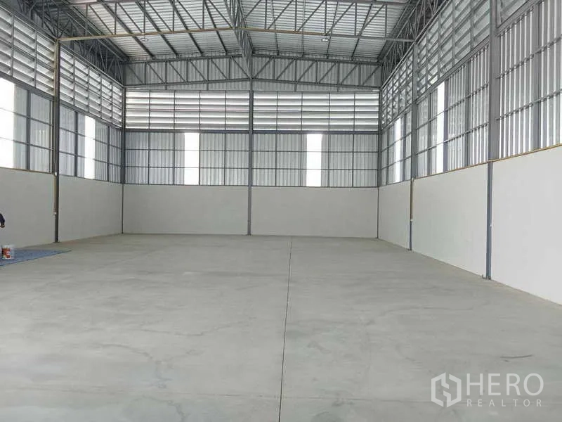 Warehouse for rent in Bang Bua Thong, Nonthaburi - Spacious warehouse interior showing high ceiling steel trusses, polished concrete floor and translucent skylight panels.