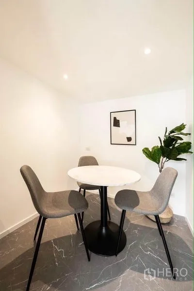 Office Space for rent in Khlong Toei, Bangkok - Small meeting room with a round white table, three grey chairs, indoor plant and marble-look flooring.