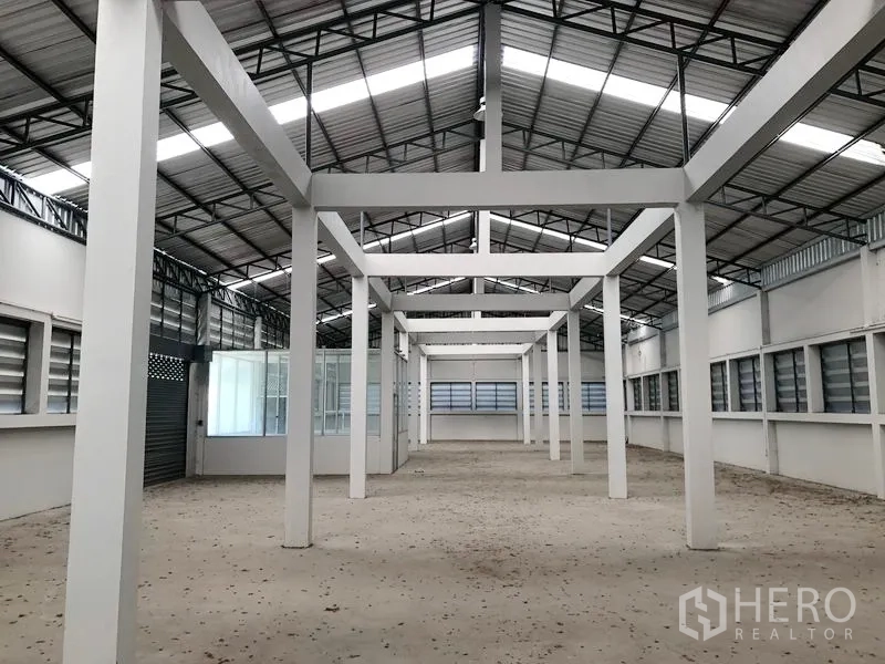 Factory for rent in Bang Bua Thong, Nonthaburi - Symmetrical view down the central aisle showing tall ceiling and skylight panels.