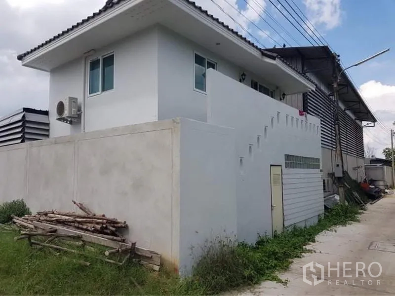 Warehouse for sale in Lam Luk Ka, Pathum Thani - Two-storey office or staff quarters adjoining the warehouse, with exterior stair and high boundary wall.