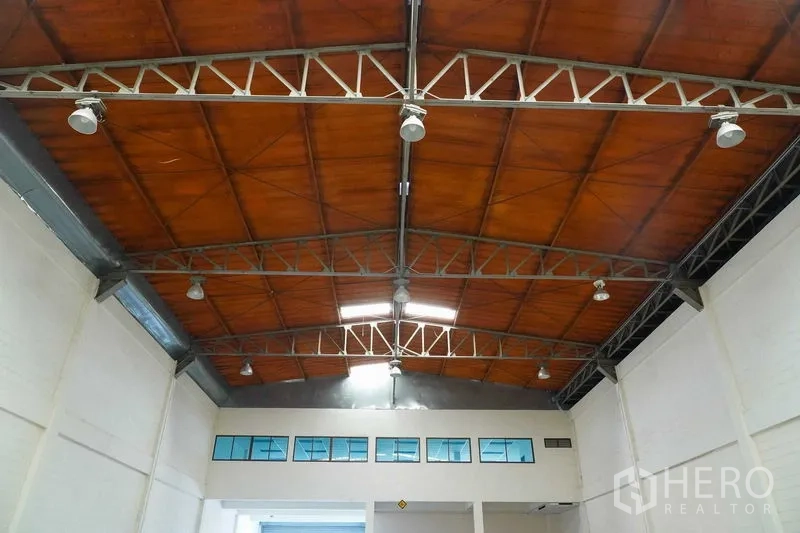 Factory for rent in Bang Sao Thong, Samut Prakan - High warehouse ceiling with steel trusses, wood panels and industrial lighting.