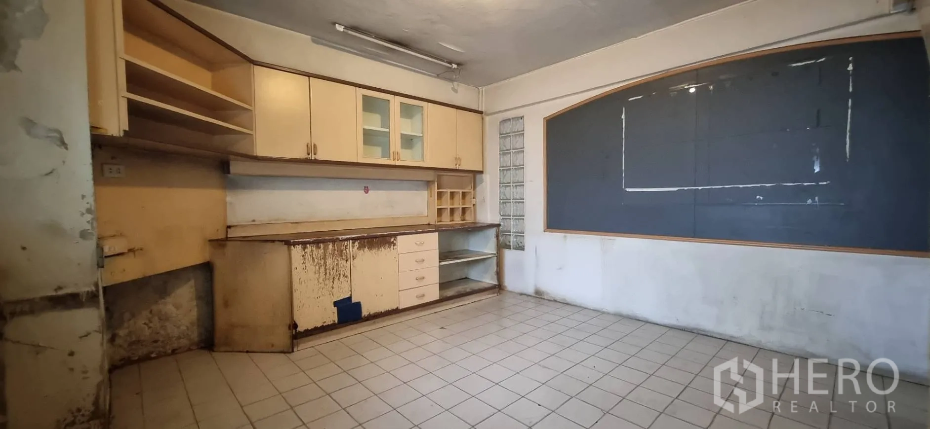 Shophouse for rent or sale in Bangkok - Back office or pantry with built-in cabinets and tiled floor needing renovation.