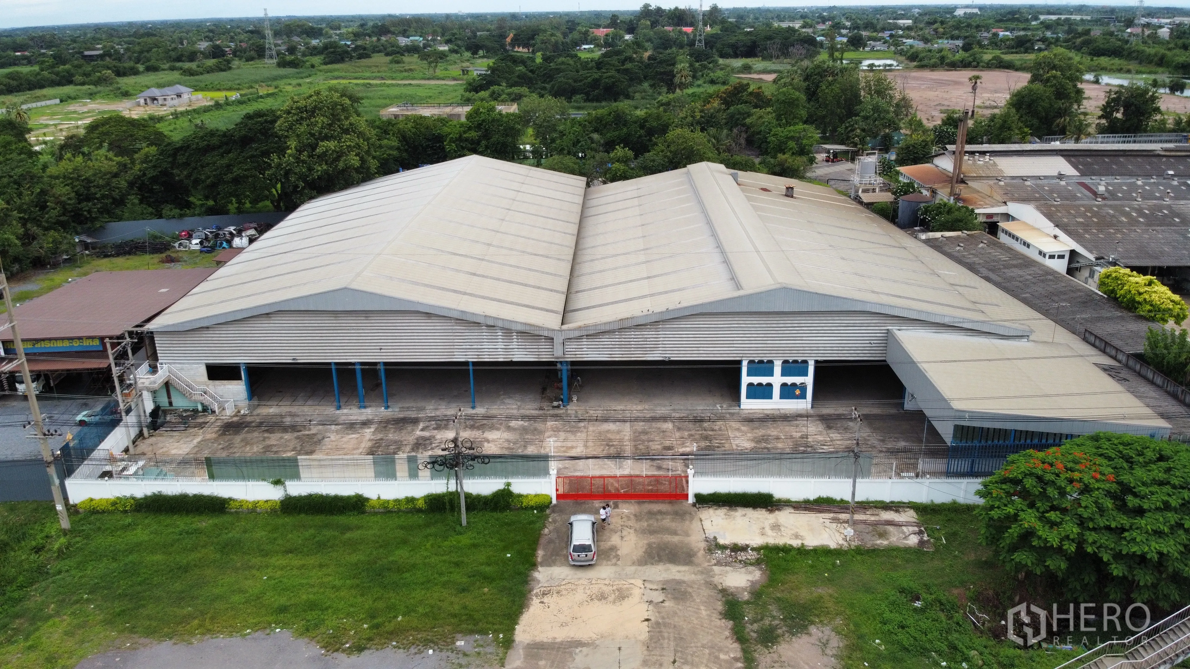 工厂 for rent in Mueang Nakhon Pathom, Nakhon Pathom - 大型双坡顶厂房与围合用地的航拍图，周边绿化环绕。