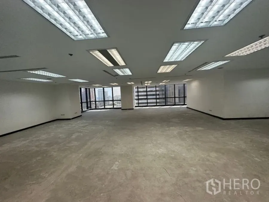 Office Space for rent in Khlong Toei, Bangkok - Large open-plan office floor with drop-ceiling lights and wide windows at both ends.