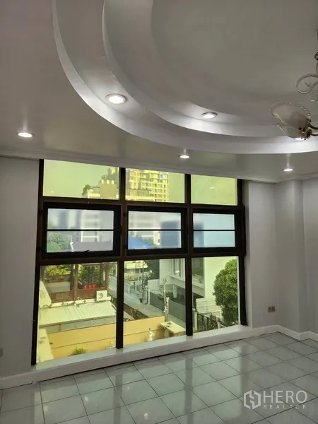 Office Space for rent or sale in Khlong Toei, Bangkok - Large window wall with recessed ceiling and downlights in a tiled office.