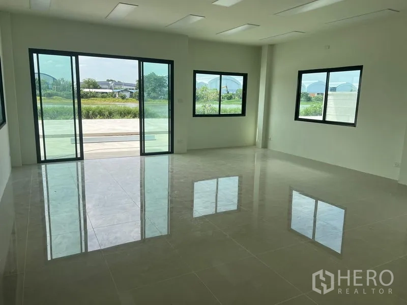 Warehouse for rent in Bang Phli, Samut Prakan - Ground‑floor office with sliding glass doors, bright tiles and views to landscaped greenery.