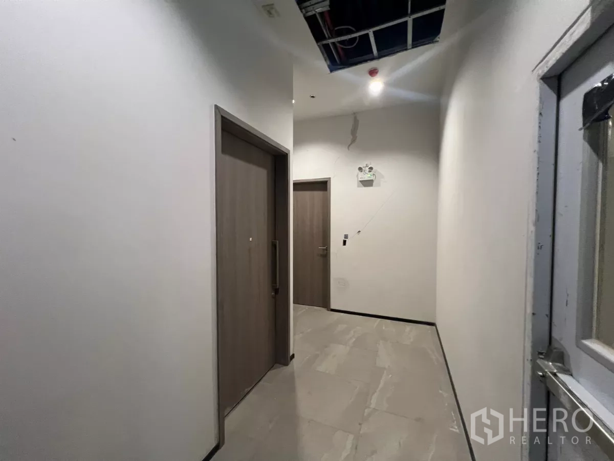 Retail Space for rent - Service corridor with tiled floor leading to storage or restroom doors.