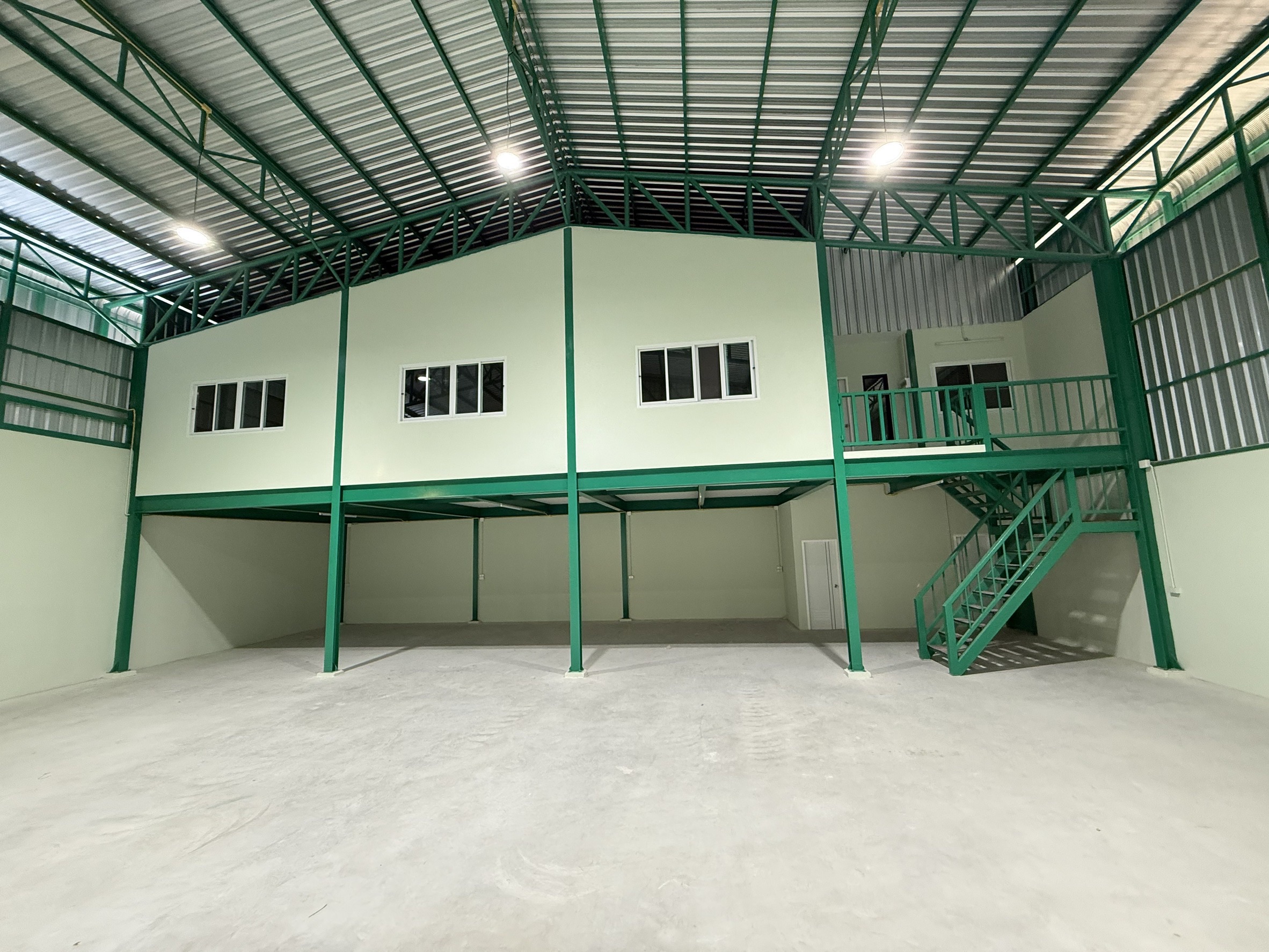 Warehouse for rent in Lat Krabang, Bangkok - Mezzanine level with windows, green steel staircase and handrails above open bay.