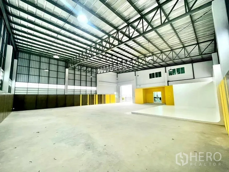 Warehouse for sale in Lam Luk Ka, Pathum Thani - Spacious warehouse interior with 6.6m high steel‑truss roof, bright lighting and large loading door.