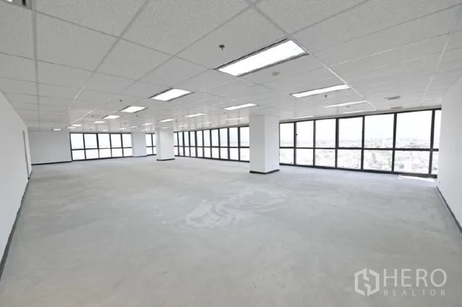 Office Space for rent in Huai Khwang, Bangkok - Spacious open-plan corner office with wraparound windows, bright grid ceiling lights and city views.
