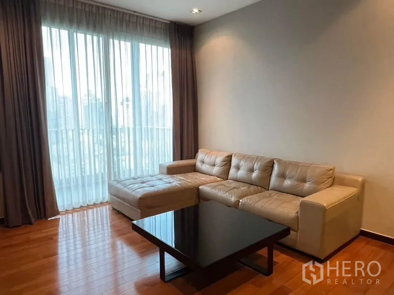Condominium for rent - Cozy seating area with sectional sofa and coffee table by large sheer‑draped windows.