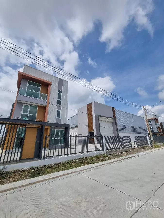 Warehouse for sale in Lam Luk Ka, Pathum Thani - Streetscape showing office building and attached warehouse behind a fence.