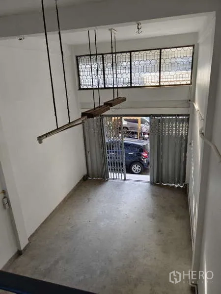 Shophouse for rent in Bang Na, Bangkok - View from mezzanine toward metal folding gates and transom windows.