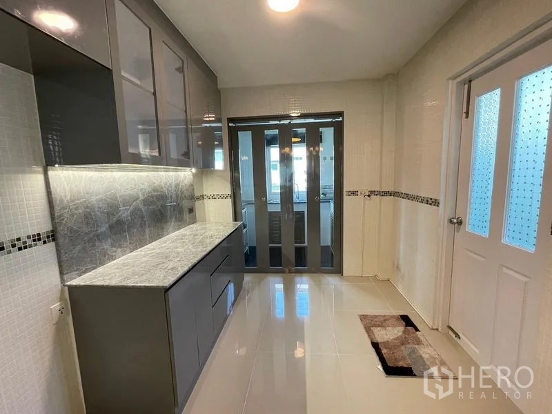 Detached House for sale in Lam Luk Ka, Pathum Thani - Modern closed kitchen with glossy grey cabinets and marble countertop.