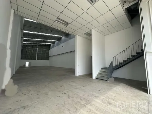 Factory for rent in Khlong Luang, Pathum Thani - Clear-span warehouse interior showing loading area and mezzanine office partition.