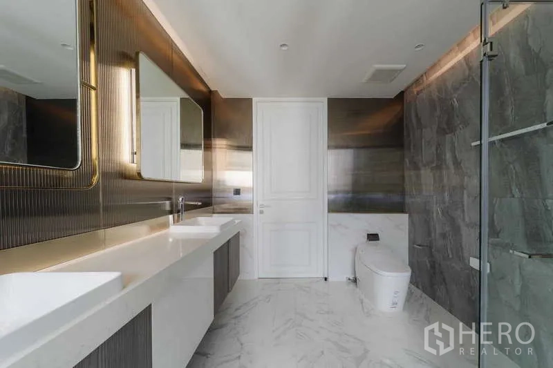 Townhouse for rent or sale in Watthana, Bangkok - Large bathroom with double vanity, smart toilet, and glass shower.