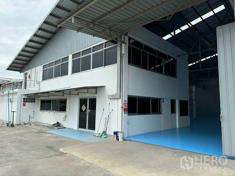 Warehouse for rent in Mueang Pathum Thani, Pathum Thani - Entrance to the two-storey office block with canopy, sliding glass doors, and adjacent loading bay.