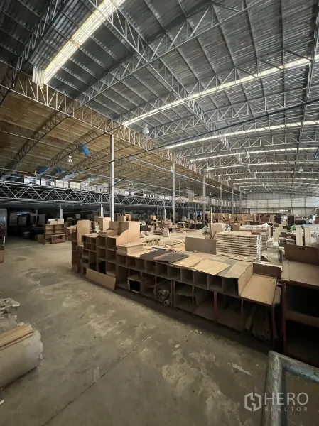 工厂 出租或出售在Sai Noi, Nonthaburi - 宽敞仓库内部，高钢桁架屋顶与夹层，材料堆放整齐