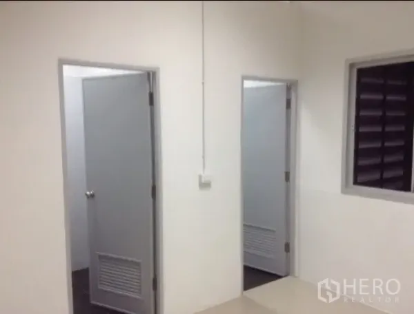 Warehouse for rent in Bang Kapi, Bangkok - Clean warehouse area showing two restroom doors and a ventilation window.