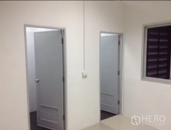 Warehouse for rent in Bang Kapi, Bangkok - Clean warehouse area showing two restroom doors and a ventilation window.