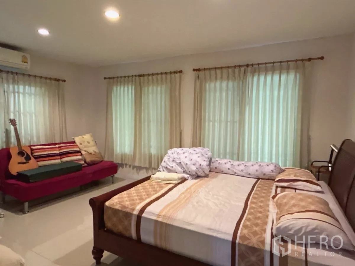Detached House for sale in Bang Kapi, Bangkok - Spacious second bedroom with sofa, guitar, and multiple curtained windows.