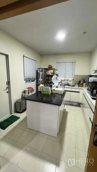 Detached House for sale in Suan Luang, Bangkok - Modern U-shaped kitchen with central island, stone countertop and ample cabinets.