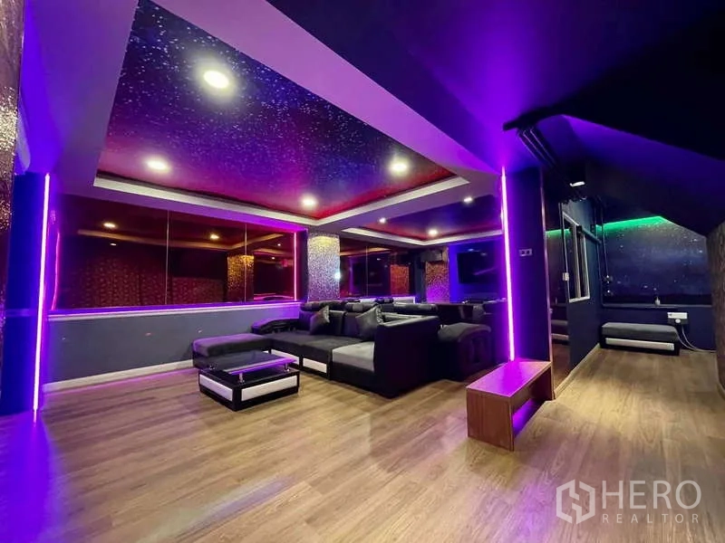 Shophouse for rent in Lat Phrao, Bangkok - Spacious lounge with wood floors and purple accent lights suitable for gatherings.