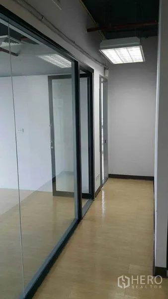 Office Space for rent in Khlong Toei, Bangkok - Hallway with floor-to-ceiling glass partitions and fluorescent lighting.