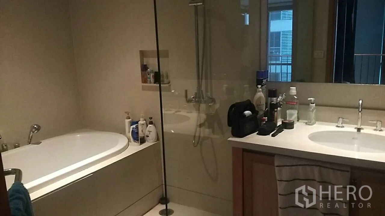 Condominium for sale in Khlong Toei, Bangkok - Bathroom with bathtub, glass-enclosed shower and wide countertop vanity.