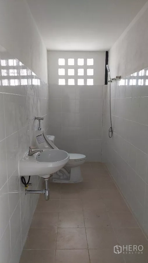Warehouse for rent in Khlong Toei, Bangkok - Clean tiled restroom with toilet, sink, and shower inside the warehouse.