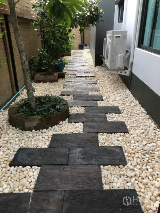 Detached House for rent in Bang Kapi, Bangkok - Low-maintenance side garden with pebble pathway, stepping stones and small trees along the house.