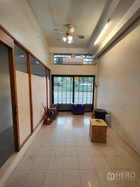 Retail Space for rent in Khlong Toei, Bangkok - Ground-floor retail room with tiled floor, ceiling fan and glass frontage secured by a grille.