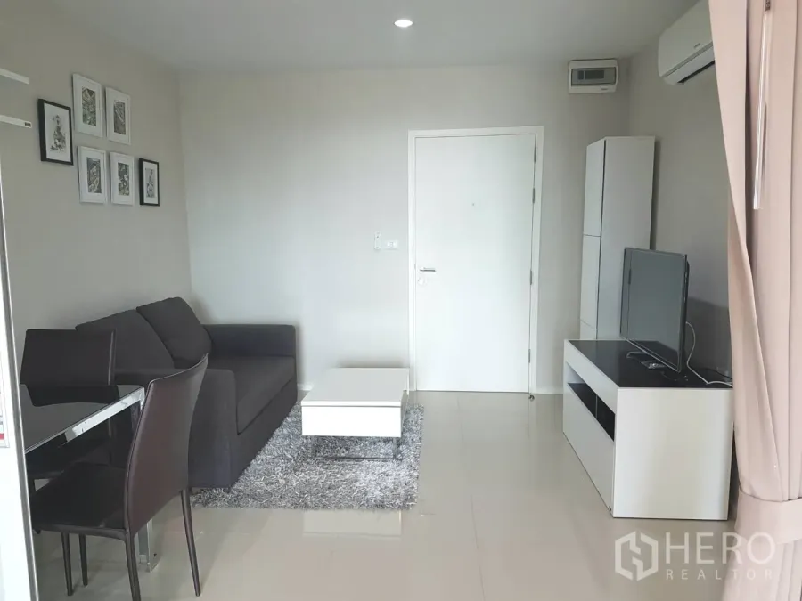 Condominium for rent or sale in Huai Khwang, Bangkok - Bright living room with gray sofa, TV console and white coffee table in a modern Bangkok condo.