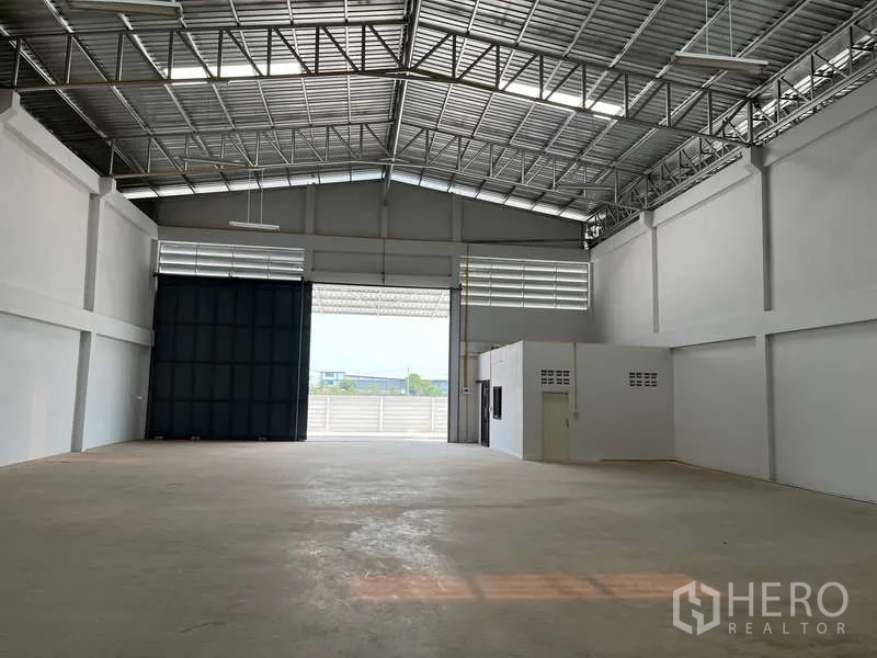Warehouse for rent in Sam Phran, Nakhon Pathom - Spacious warehouse interior with high clear‑span steel roof, skylights, concrete floor, and wide roller shutter.